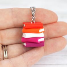 a hand holding a small stack of books on a ball chain with a ring around it