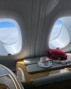 the interior of an airplane with two windows and a cup of coffee in front of it