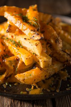 some fries are on a black plate with parsley sprinkled around them and garnished with seasoning