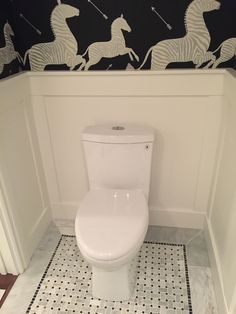 a white toilet sitting inside of a bathroom next to a black and white wallpaper