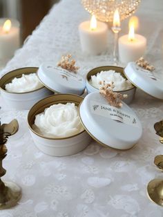 several small white dishes on a table with some candles in the background and one bowl filled with whipped cream