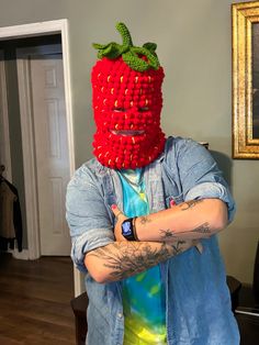 a man wearing a red strawberries mask with his arms crossed in front of him