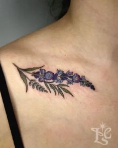 a woman's chest with purple flowers and leaves on the left side of her body