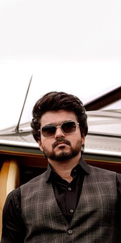 a man wearing sunglasses standing next to a surfboard