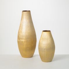 two gold vases sitting next to each other on a table