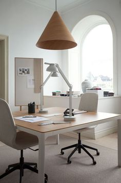 an office desk with a lamp and chair in front of the window, next to a framed photograph