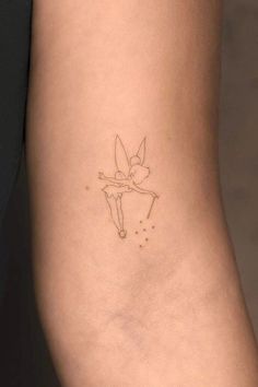 a small tattoo on the back of a woman's leg, with a fairy tinker