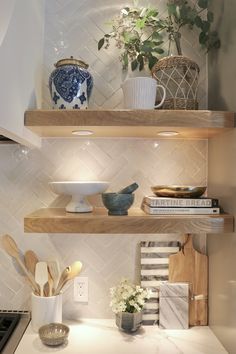 some shelves in a kitchen with bowls and utensils on them next to a potted plant