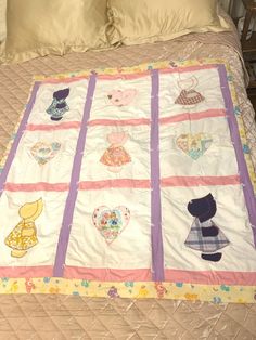 a bed with a quilt on it that has many different things on it and is next to pillows