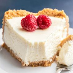 a piece of cheesecake with two raspberries on top