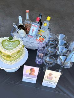 a table topped with lots of different types of food and drink glasses next to a cake