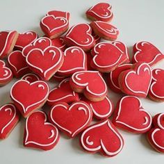 red and white heart shaped cookies are on a table next to some other small ones