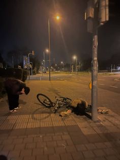 a bicycle that is laying on the ground next to a lamp post and street light