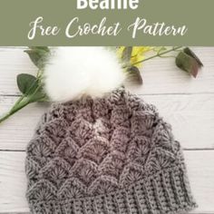 a crocheted beanie with a white pom - pom sitting on top of it