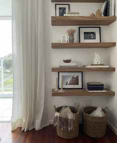 three wooden shelves with pictures and other items on them in the corner of a room