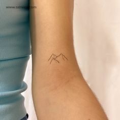 a woman's arm with a small mountain tattoo on the left side of her arm