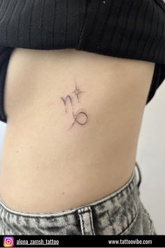 a woman's lower back tattoo with the letter m on it