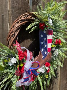 a wreath with an american flag on it hanging from the side of a wooden fence