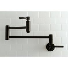 a black wall mounted hook on a white brick wall with the handles pointing up and down