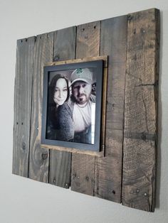 a wooden frame with a photo hanging on the wall next to a couple's face