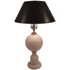 a white table lamp with a black shade on the base and a small light bulb