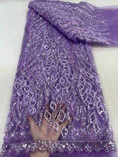 a person's hand on top of a purple dress with silver sequins