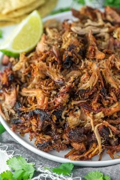 a white plate topped with shredded meat and garnished with cilantro