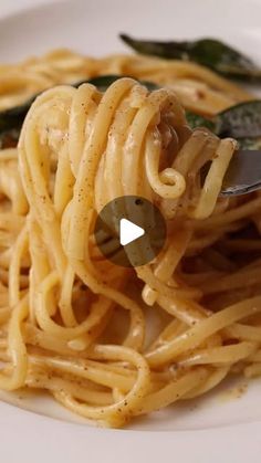 a white plate topped with pasta and sauce next to a green leafy vegetable on top of it