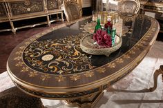 a fancy dining room table with flowers on the center and chairs around it in front of an ornate mirror