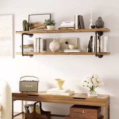 two wooden shelves with books, vases and other items on them in a living room