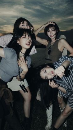 three young women posing for the camera in front of a cloudy sky