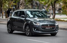 a black suzuki swift is driving down the street