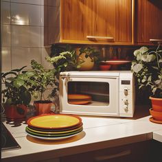 a white microwave oven sitting on top of a kitchen counter next to potted plants