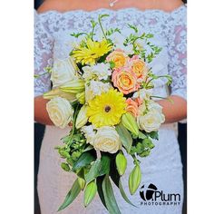 a bride holding a bouquet of yellow and white flowers