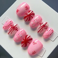 Pink Candy cane press on nails to have you looking like you just spent all your dollars at the nail salon. Skip the countless hours sitting, and save your hard earned cash and get these handmade press on nails instead. Featuring pink and red details, these nails are made to order, reusable and oh so cute! Adding a little fun to the traditional red and green colors of Christmas, these nails are perfect for a fun holiday party! Whether you want to go the extra mile for a special event, or just want to feel fancy in your day to day life, these precious custom press on nails are for you. ✨ ✨style pictured is extra short round ✨FREE application kit included with first purchase! (includes alcohol wipe, glue, nail file and cuticle pusher) ✨ Make sure to read the instructions on how to accurately Pink Christmas Nails Candy Canes, Santa Hat Nails Design, Bow Nails Christmas, Non Traditional Christmas Nails, Red And Pink Christmas Nails, Pink Christmas Nails Almond, Candyland Nails, Pink Candy Cane Nails, Light Pink Christmas Nails