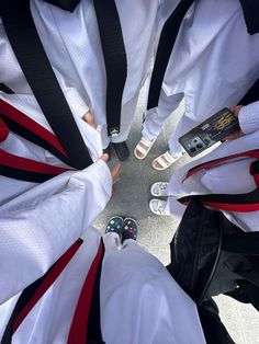 a group of people standing in a circle wearing white and red outfits with black straps