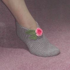 a woman's feet wearing knitted slippers with pink flowers on the side