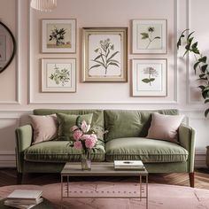 a living room with pink walls and green couches, framed pictures on the wall