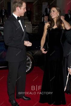 a man and woman in formal wear standing next to each other on a red carpet