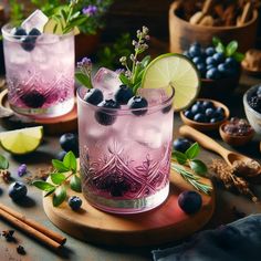 two glasses filled with blueberries and limeade sitting on top of a wooden cutting board