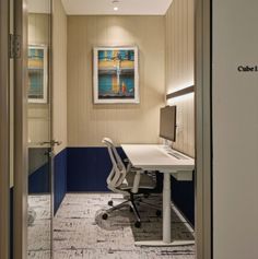 an office with a desk and chair in the corner, looking into the hallway from another room