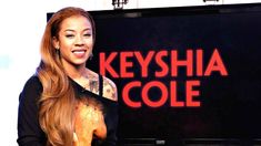 a woman standing in front of a sign that says keyshia cole on the side