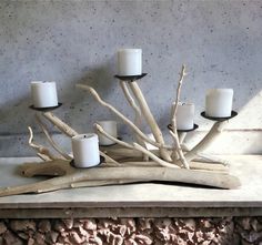 candles are arranged on driftwood in front of a concrete wall