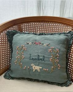 an embroidered pillow on a wicker chair with the words love and a dog in it