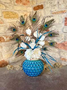 a blue vase filled with white flowers and peacock feathers