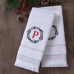 two white towels with the letter p on them next to pine cones and evergreen branches