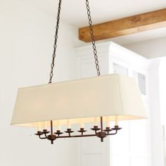 a chandelier hanging from the ceiling in a room with white walls and wood beams