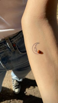 a person with a small tattoo on their arm and the moon behind them is shown