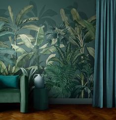 a green couch in front of a wall with plants on it and a vase next to it