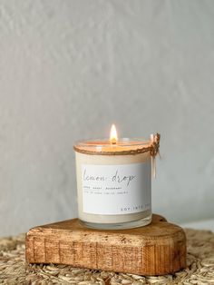 a white candle sitting on top of a wooden block next to a wall and rug